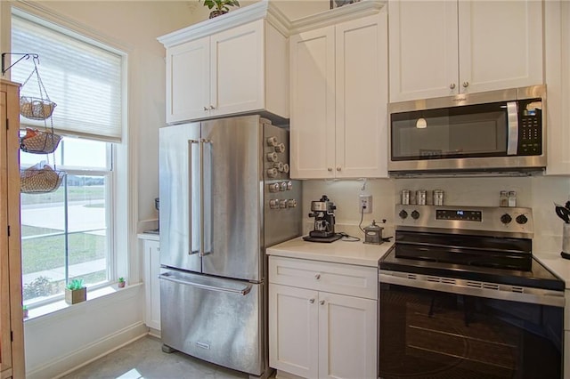 kitchen featuring appliances with stainless steel finishes, white cabinetry, light countertops, and baseboards