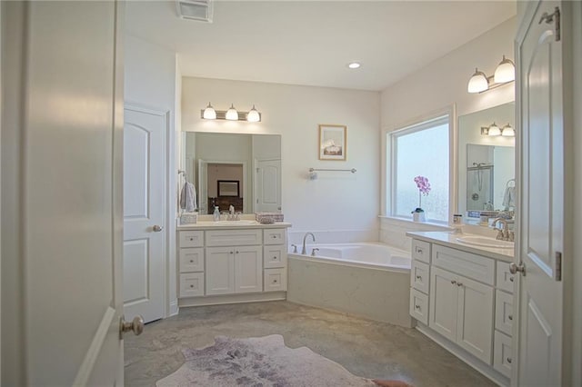 bathroom with a garden tub, two vanities, visible vents, and a sink