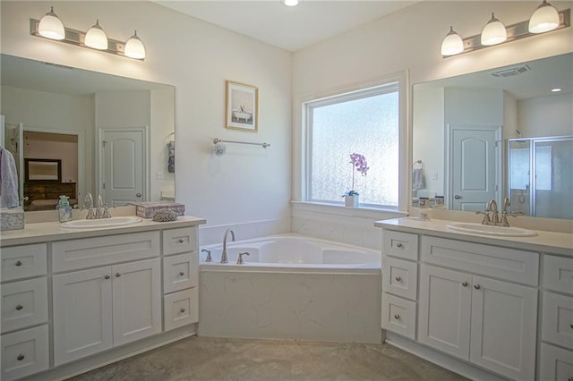 full bathroom with visible vents, a shower stall, two vanities, and a sink