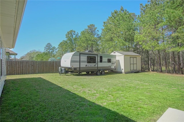 view of yard featuring a storage unit, an outbuilding, and a fenced backyard