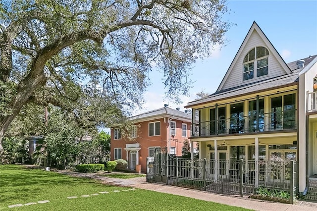 back of property with a yard, a balcony, and fence