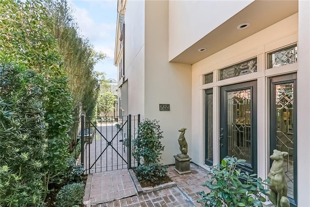 view of exterior entry with a gate and stucco siding