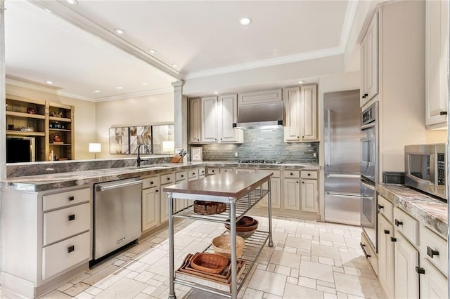 kitchen with a sink, ventilation hood, appliances with stainless steel finishes, a peninsula, and decorative backsplash