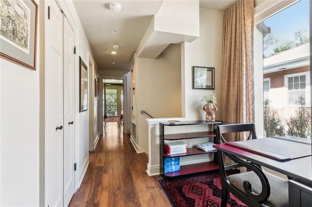 corridor featuring baseboards and dark wood-style floors