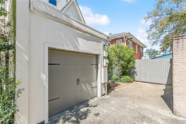 garage featuring concrete driveway and fence