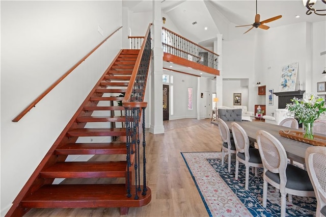 dining room featuring wood finished floors, stairway, a ceiling fan, and high vaulted ceiling