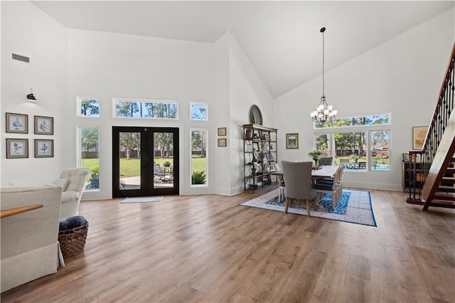 entryway featuring visible vents, high vaulted ceiling, wood finished floors, a chandelier, and stairs