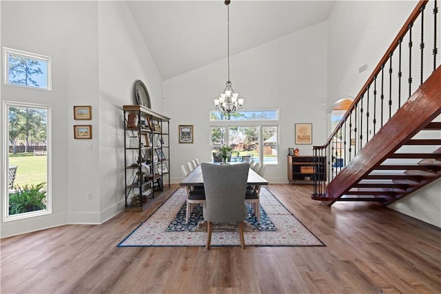 dining area featuring stairway, baseboards, an inviting chandelier, and wood finished floors