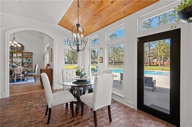 dining area featuring arched walkways, wood ceiling, brick floor, and a chandelier