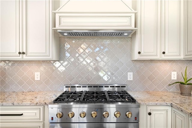 kitchen with decorative backsplash, stove, and cream cabinetry