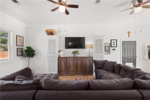 living area featuring visible vents, crown molding, and a ceiling fan