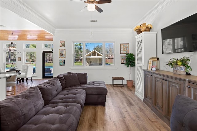 living area featuring visible vents, light wood-style flooring, crown molding, and ceiling fan with notable chandelier