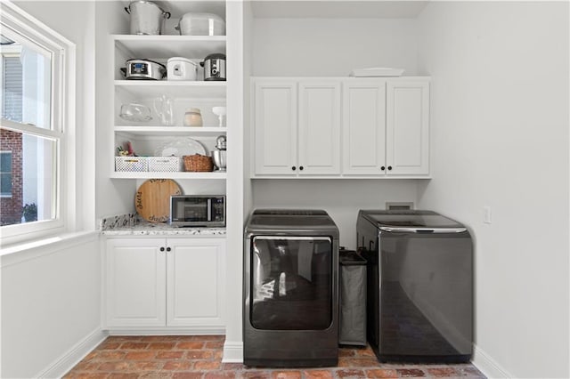 washroom with brick floor, baseboards, cabinet space, and independent washer and dryer