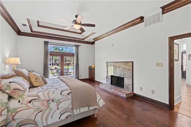 bedroom featuring a raised ceiling, access to outside, wood finished floors, and visible vents