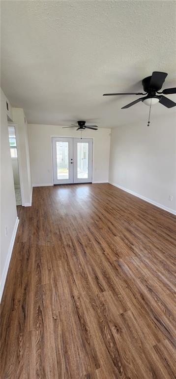 spare room with dark wood-style floors, french doors, baseboards, and a textured ceiling