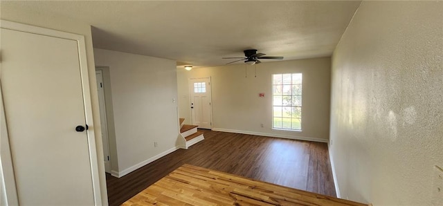 spare room featuring baseboards, ceiling fan, wood finished floors, stairs, and a textured wall