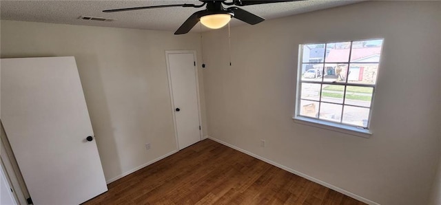 unfurnished bedroom featuring wood finished floors, baseboards, visible vents, ceiling fan, and a textured ceiling