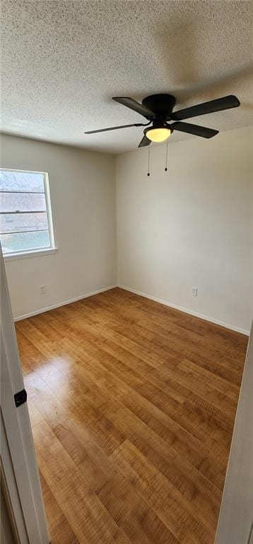 unfurnished room with a textured ceiling, baseboards, light wood-type flooring, and ceiling fan