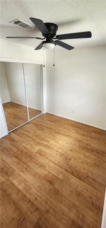 unfurnished bedroom featuring a ceiling fan, light wood-style floors, a closet, and a textured ceiling