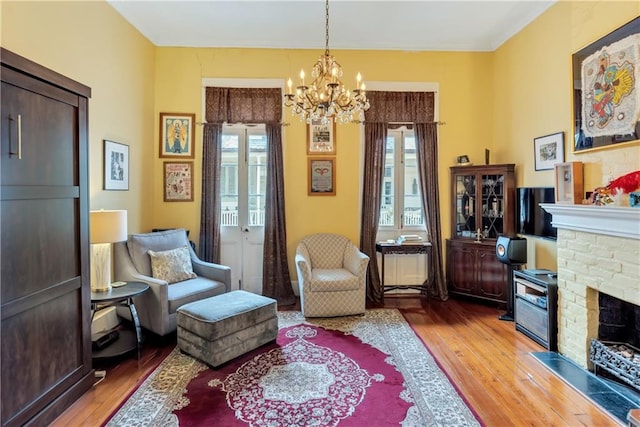 sitting room featuring a fireplace, an inviting chandelier, and light wood-style floors