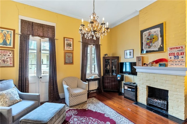 living room featuring a chandelier, a fireplace, crown molding, and wood finished floors