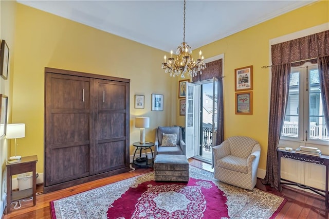 living area with baseboards, wood finished floors, radiator, and a chandelier