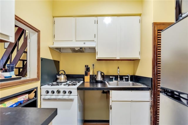 kitchen featuring under cabinet range hood, a sink, dark countertops, white cabinetry, and white range with gas stovetop