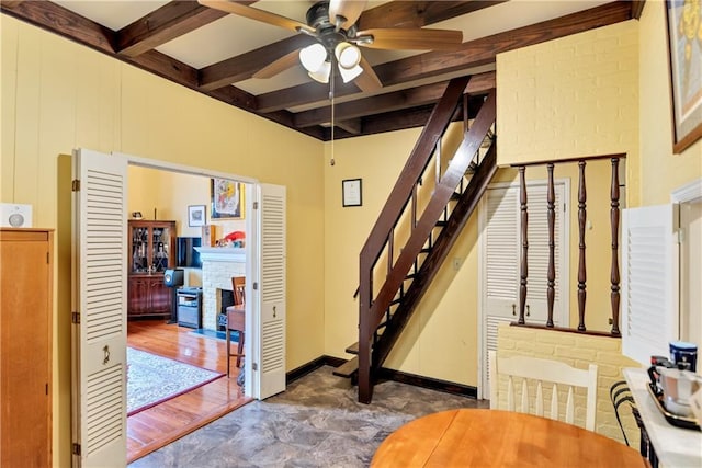 stairs featuring beamed ceiling, a ceiling fan, coffered ceiling, a fireplace, and baseboards