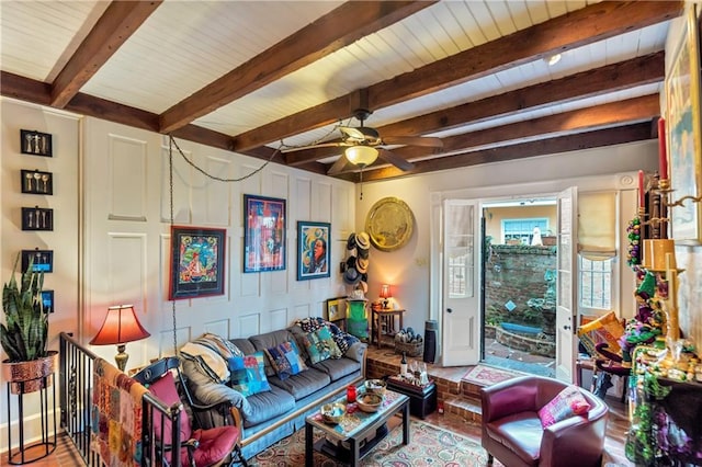 living room with beam ceiling, wood finished floors, a ceiling fan, and baseboards