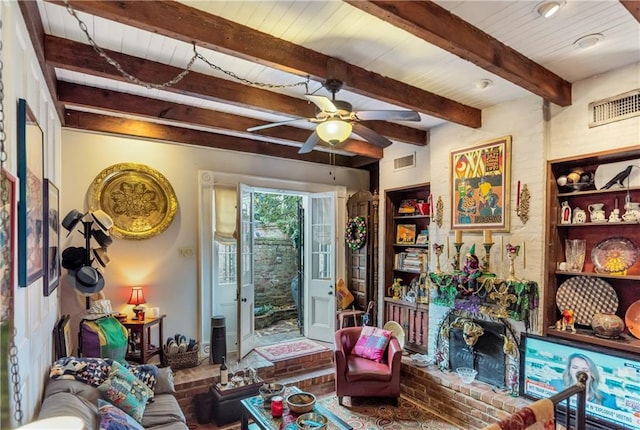 living area featuring beam ceiling, a ceiling fan, visible vents, and wooden ceiling