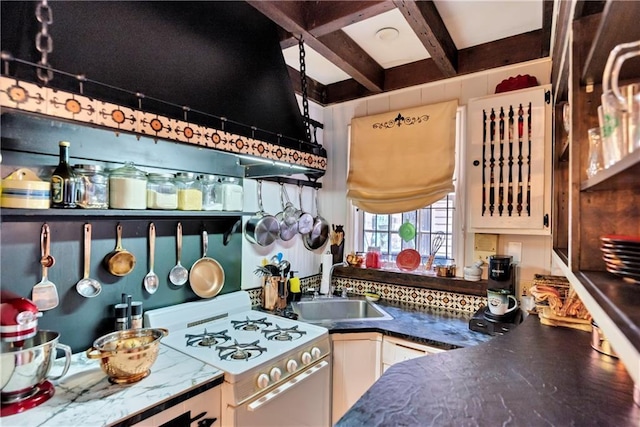 kitchen featuring a sink, beam ceiling, white gas stove, and white cabinetry