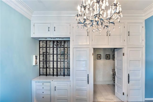 kitchen with baseboards, an inviting chandelier, crown molding, and white cabinetry