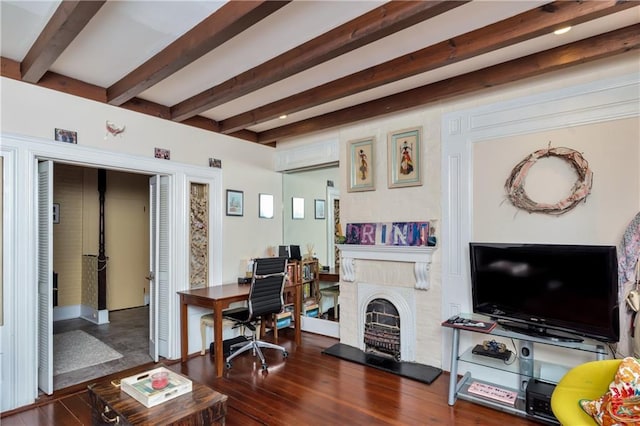 living room with a wall unit AC, beamed ceiling, dark wood-style floors, and a fireplace with raised hearth