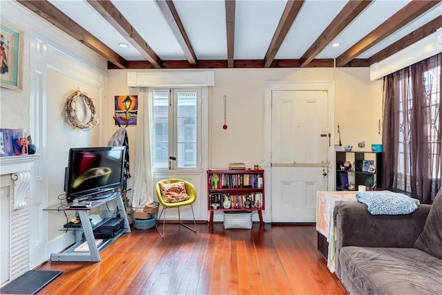 living area featuring beamed ceiling, a healthy amount of sunlight, and hardwood / wood-style floors