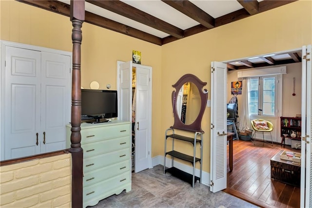 bedroom with beamed ceiling, baseboards, and wood finished floors