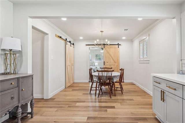 dining room featuring a barn door, crown molding, visible vents, and light wood-type flooring