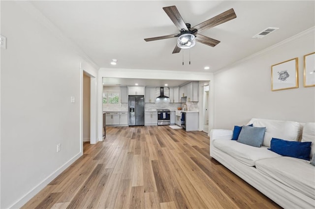 living room featuring baseboards, a ceiling fan, crown molding, and light wood-style floors