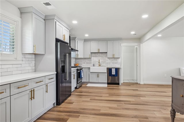 kitchen with a sink, light countertops, light wood finished floors, and stainless steel appliances