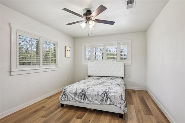 bedroom with visible vents, multiple windows, and wood finished floors