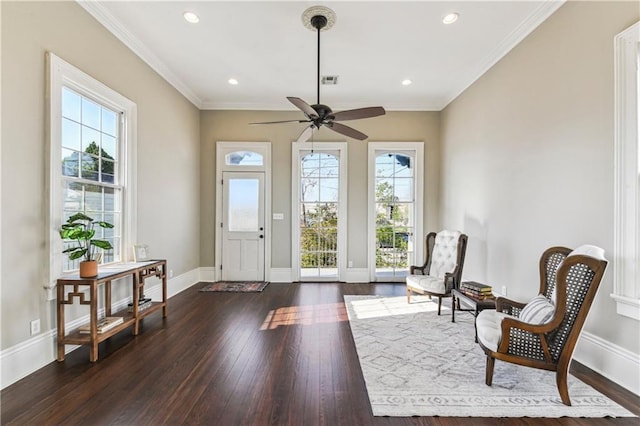 living area with dark wood finished floors, crown molding, baseboards, and a wealth of natural light