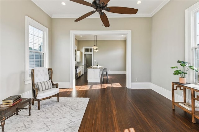 sitting room with dark wood-style floors, baseboards, ceiling fan, and ornamental molding