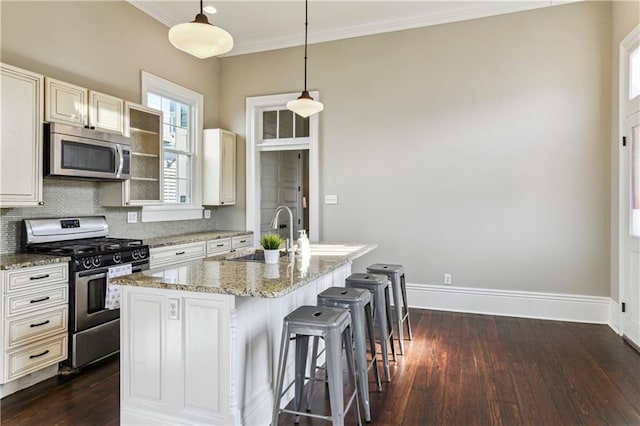 kitchen with dark wood-type flooring, a sink, a kitchen breakfast bar, stainless steel appliances, and baseboards