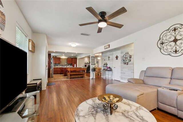 living room featuring wood finished floors, visible vents, and ceiling fan