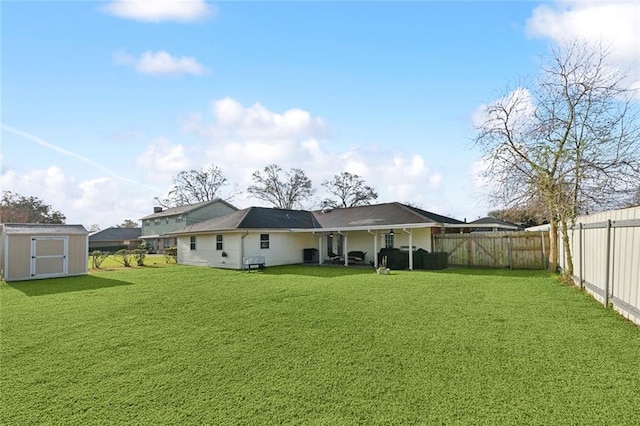 back of house with an outbuilding, a fenced backyard, a storage unit, and a yard