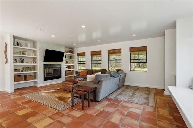 tiled living room with built in features, baseboards, a large fireplace, and recessed lighting