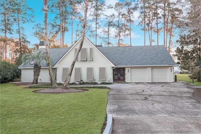 view of front of home featuring driveway, a front yard, a garage, and a shingled roof