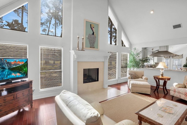 living room featuring wood finished floors, baseboards, visible vents, high vaulted ceiling, and a fireplace