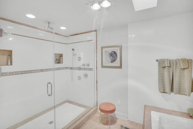 bathroom with a stall shower, a washtub, a skylight, tile patterned flooring, and baseboards