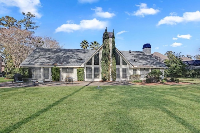 rear view of house featuring a yard, a chimney, and a patio