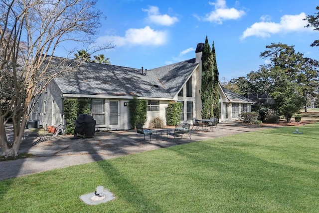 back of house featuring a yard, a patio area, and a chimney